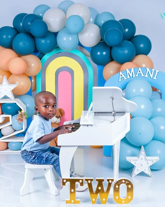 Birthday photoshoot at a toy piano, teal balloon arch