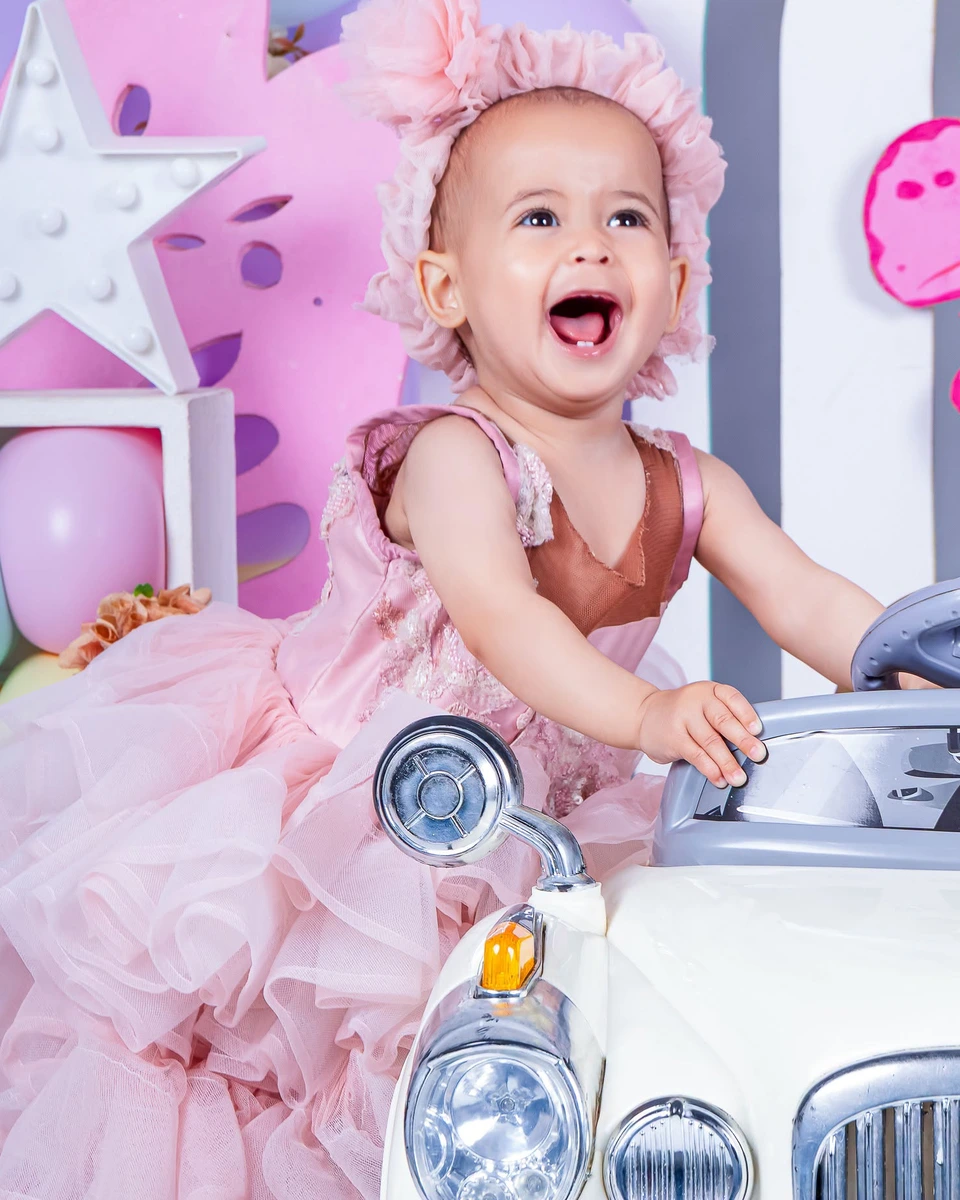 First birthday photoshoot, girl in a pink tulle dress on a toy car