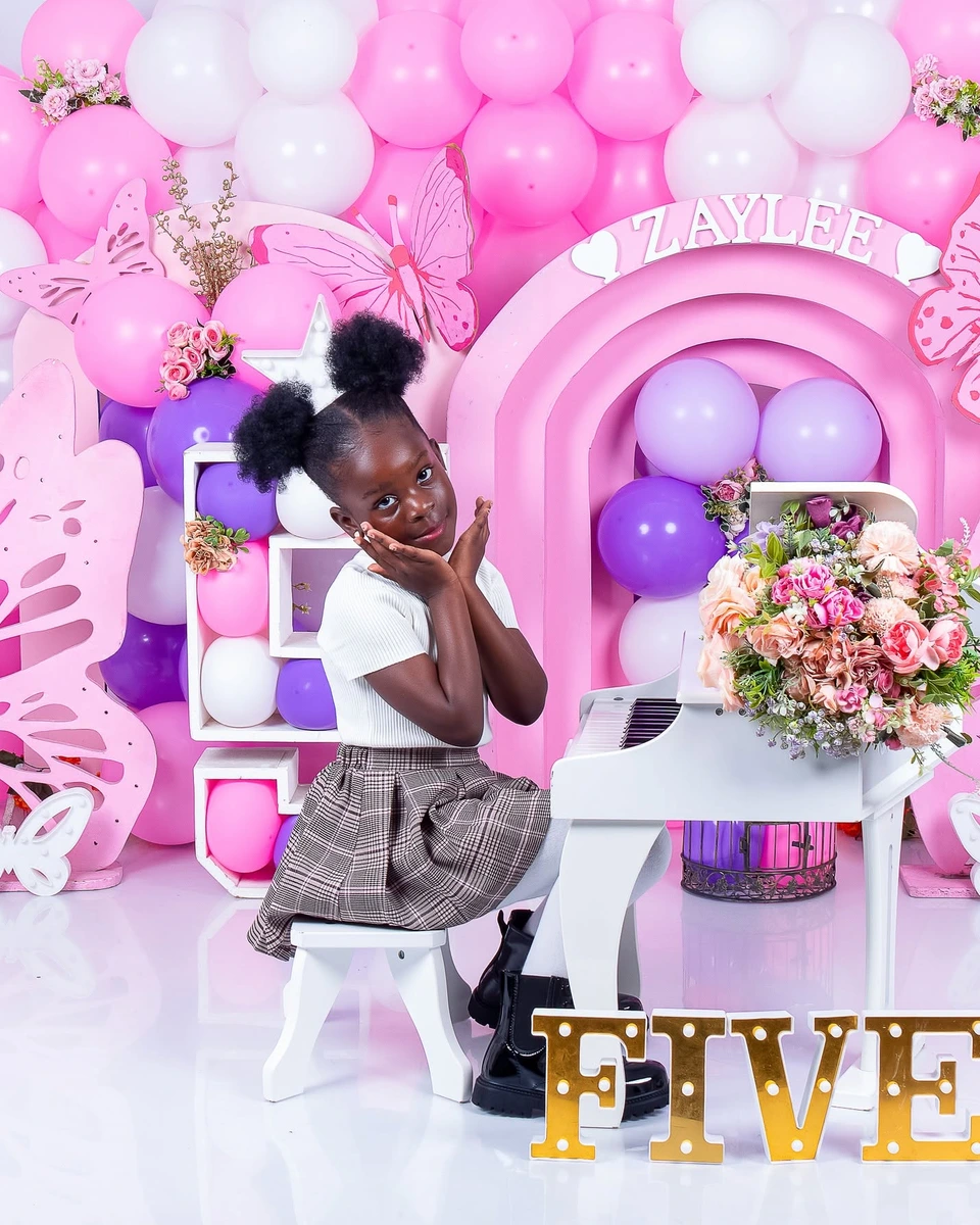 Birthday photoshoot at a toy piano with a pink balloon arch